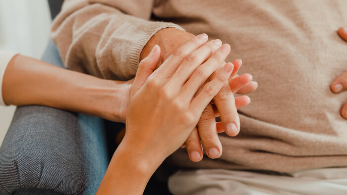 Close up of caregiver holding patient's hand.