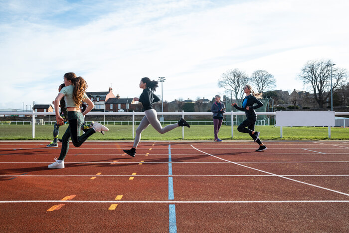 Student-athletes running on field track.