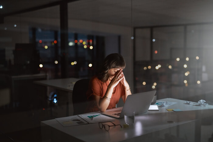 Woman in dark office looking overwhelmed with work.