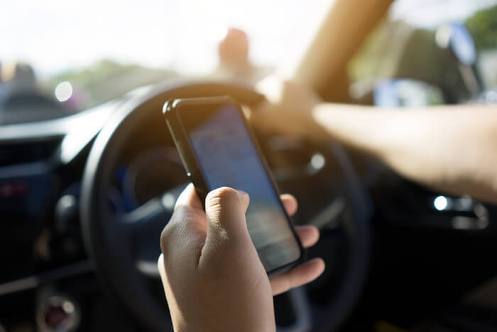 Close-up of driver staring at phone instead of the road.