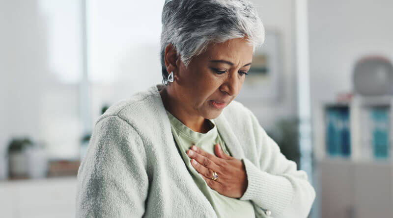Older woman putting her hand to her chest, looking worried.