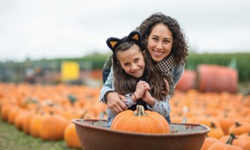 Mom and daughter smile while at a pumpkin patch