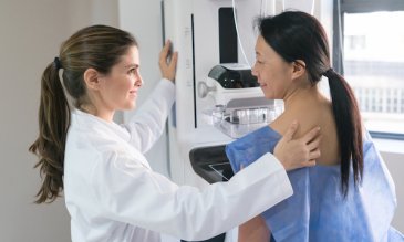 Technician providing mammogram for patient