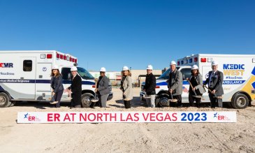 Group poses who tossed dirt on groundbreaking for Valley ER at North Las Vegas in front of sign that says coming late 2023
