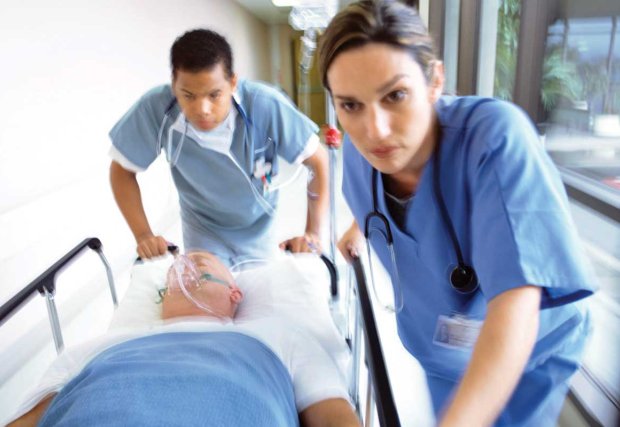 Medical staff wheeling patient quickly through hallway