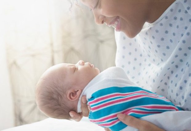 A woman holding her newborn baby in her hospital bed