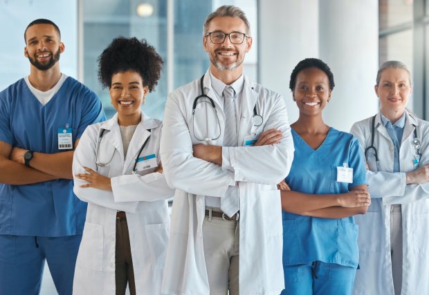 Stock photo of five medical professionals standing in a line with their arms crossed and smiling