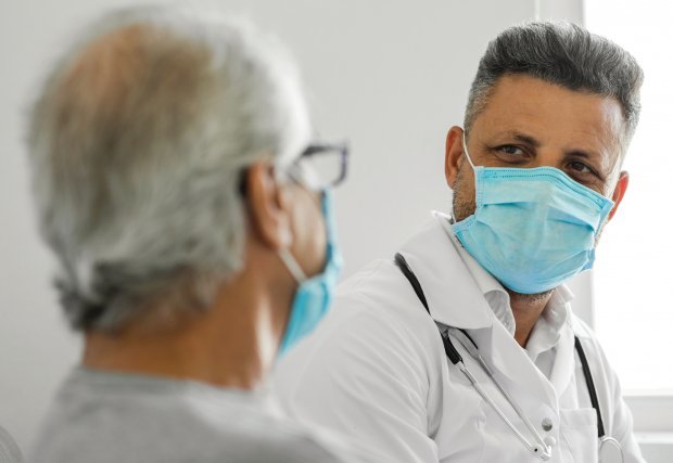 Doctor hablando con el paciente mientras está enmascarado