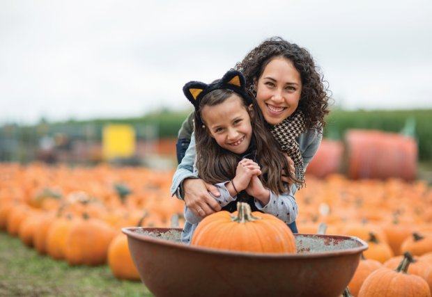 Mom and daughter smile while at a pumpkin patch