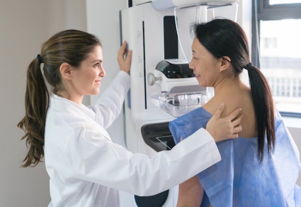 Technician providing mammogram for patient
