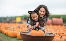 Mom and daughter smile while at a pumpkin patch