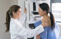 Technician providing mammogram for patient