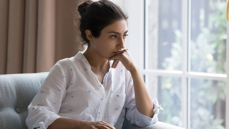 Young woman looking out the window, deep in thought.